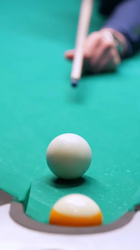 Close-up vertical billiards shot as cue ball and striped ball drop into corner Stock Footage 327889391
