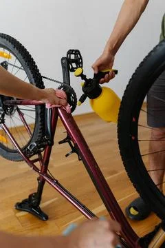 Close-up vertical cropped shot of two biker cleaning mountain bike using water Stock Photos
