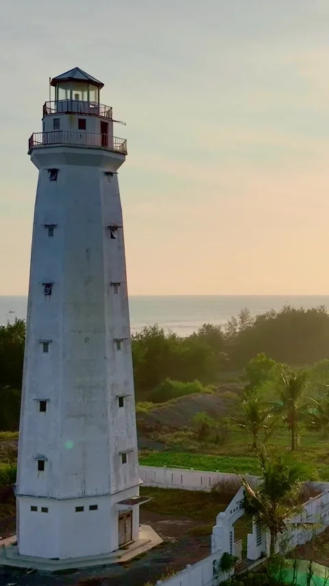 Close vertical lighthouse beside ocean at sunset Stock Footage 335432344