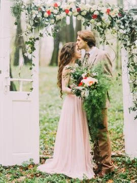 The close-up vertical photo of the groom in vintage suit kissing his bride with Stock Photos