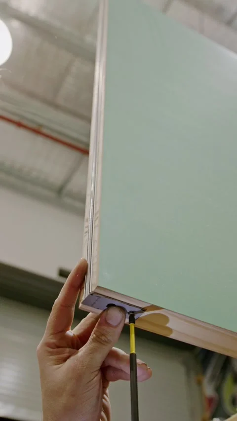 Close-up, vertical shot of a craftsman securing a metal corner bracket to Stockbeeldmateriaal 333932900