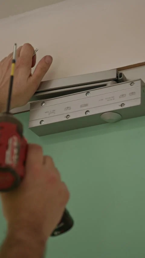 Close-up vertical shot of a technician adjusting an overhead door closer Video stock 334583056