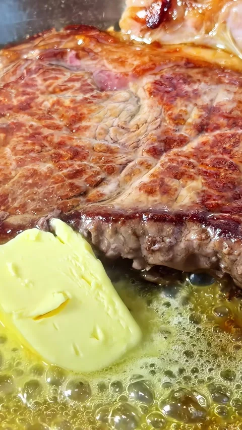 Close-up vertical social ratio video of a steak and butter cooking in a pan Stock Footage 336946043