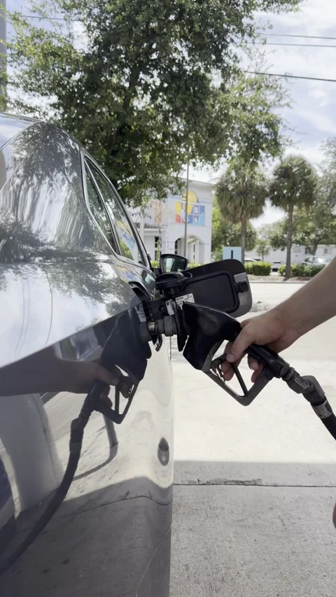 Close up vertical video of a man's hand removing a gas pump nozzle from a ca Stock Footage 343670116