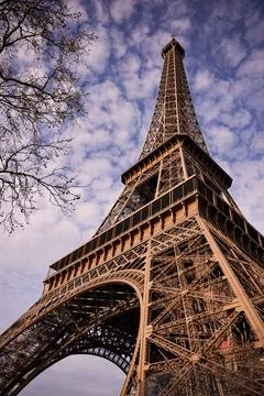 Close-up vertical view of Eiffel Tower against dramatic cloudy sky in Paris Stock Photos