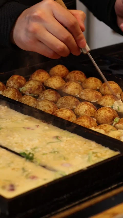 Close Up Vertical View of Hands Flipping Takoyaki Balls on Grill 動画素材 327272700