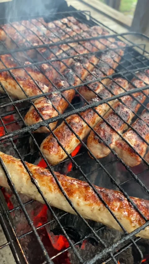 Close up, vertical view of sausages sizzling on grill Stock Footage 308280442