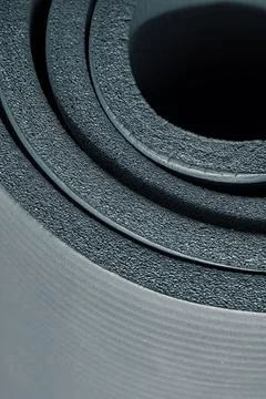 Close up vertical view of soft black rolled fitness foam mat for exercises Stock Photos