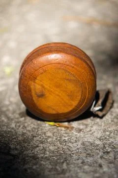Close up vertical view of traditional brown wooden yoyo resting upright on .. Stock Photos