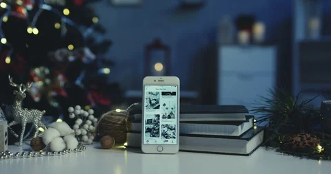 Close up of the vertical white smartphone with Christmas pictures leaning on the Stock-Footage 99809096