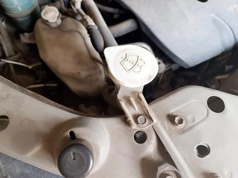 Close-up of a very dusty car engine bay, highlighting the windshield washer.. Stock Photos