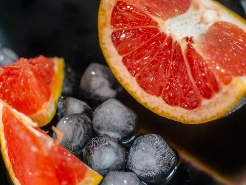 Close-up of vibrant grapefruit slices placed on glossy black surface. Фото