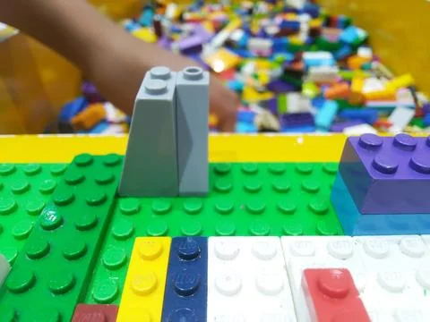 Close-up of vibrant plastic building bricks on a green baseplate with a child Stock Photos
