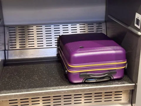 A close-up of a vibrant purple hard-shell suitcase with yellow accent strip.. Stock Photos