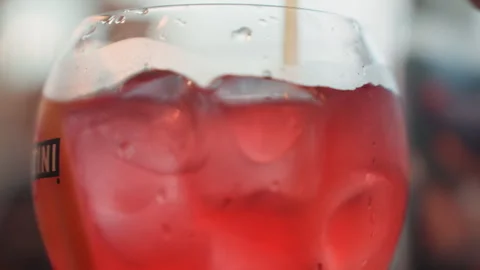 Close up of vibrant red beverage in glass with ice and condensation featuring Stock Footage 345974483