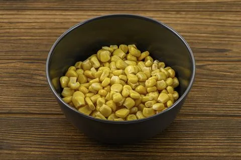 The  Close-up of vibrant yellow corn kernels in a sleek black clay bowl Foto stock