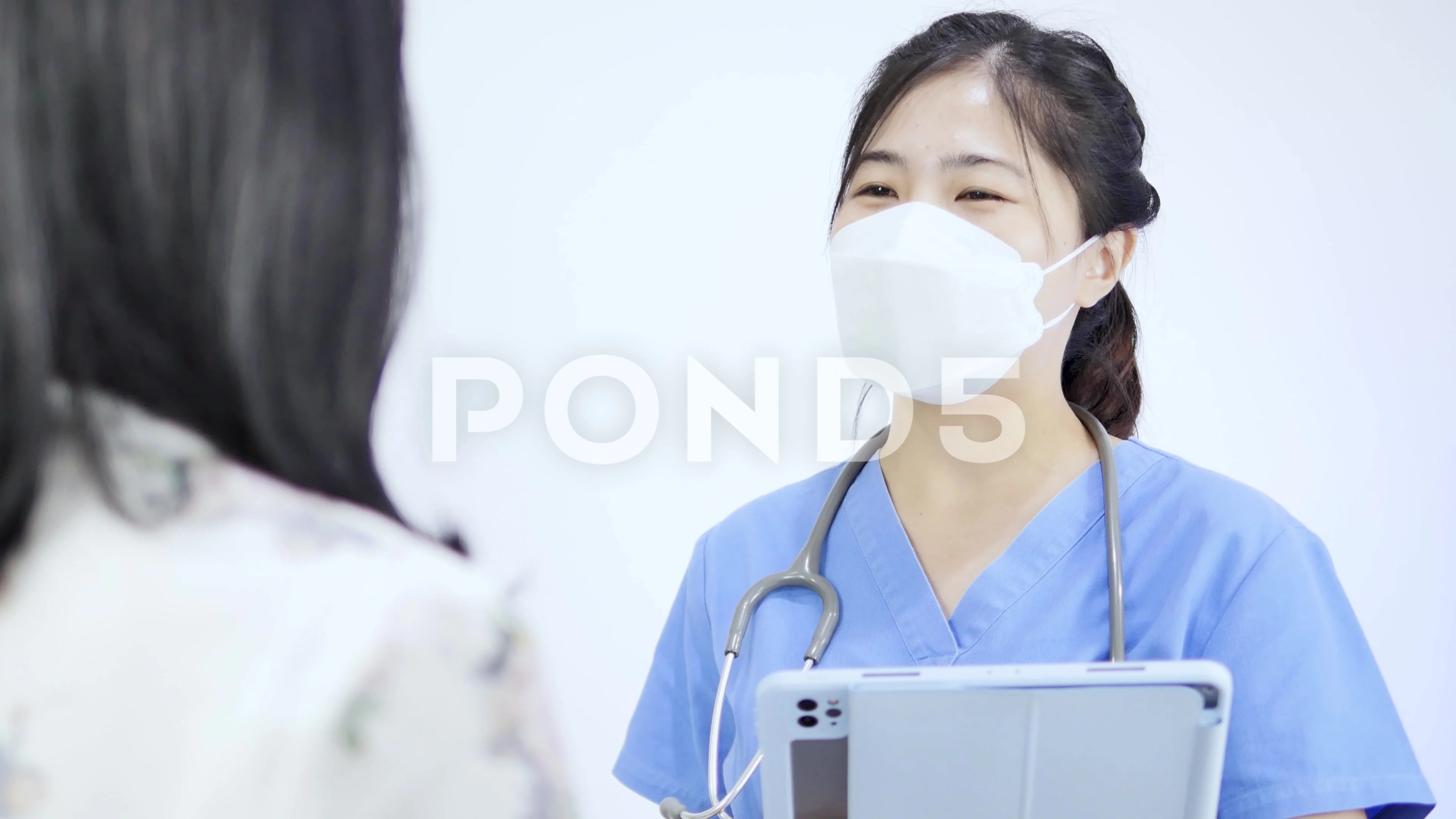 Close-up video of an Asian female doctor wearing a mask talking to a  healthcare