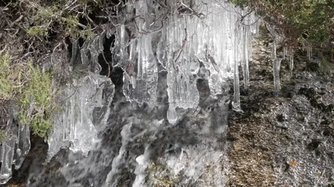 A close-up video captures icicles hanging by a waterfall in the snowy Stock Footage 293713668