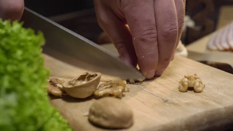 Close up video: chef cuts walnuts on the wooden board, cooking salad, vitamin Stock Footage 113820876