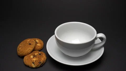 Close up video of coffee pouring into white cup with cookies. Zoom in. Stock Footage 85642832