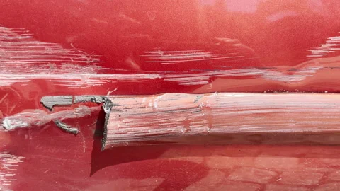 Close up video of a deep scratch and dent on a red car door caused by a Stock Footage 308647523