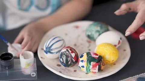 A close up video of the egg painting process. A little girl paints a Stock Footage 103331221