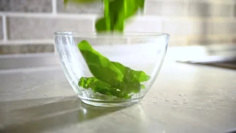 Close-up video footage of falling fresh green spinach leaves in a transparent gl Video stock 155993038