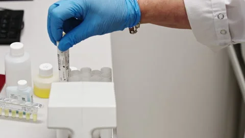Close-up video of a gloved hand putting a test tube in an automated lab. Lab Stock Footage 232488198