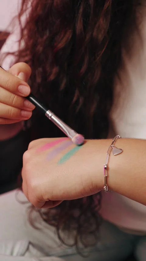 A close-up video of hands applying shimmering glitter makeup. Stock Footage 327463792