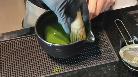 Close up video of hands whisking organic green tea powder with a bamboo. Stockbeeldmateriaal 345289913