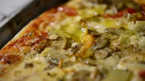 A close-up video of a homemade rectangular pizza topped with ham, artichoke.. 動画素材 302236531