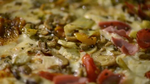A close-up video of a homemade rectangular pizza topped with ham, artichoke.. 動画素材 302236538