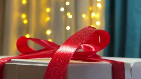 Close up video. Magic dust falling on white gift box with red bow Stock Footage 318975300
