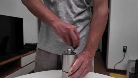 Close-up video of a man grinding beans on a kitchen table using a hand coffee Stock Footage 318342135