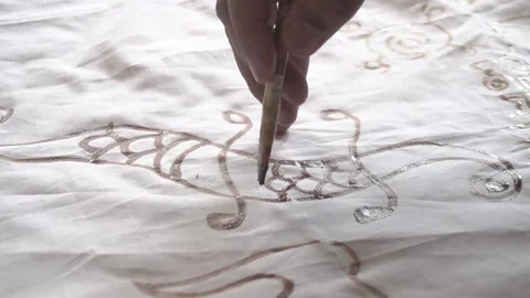 Close up video of a man making a batik pattern with melted wax (malam) Stock Footage 146761733