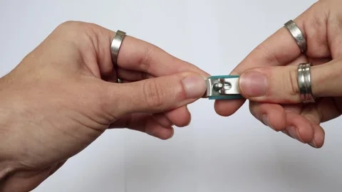 Close-up video of a man with silver rings on his fingers cutting his fingernails Stock Footage 324704137