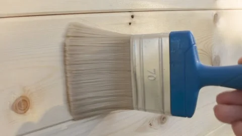 Close-up video of a paintbrush evenly applying a primer on a wooden surface, Stock Footage 291942487