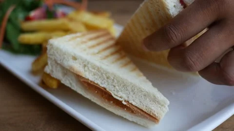 Close up video of a person's hand picking up a piece of toasted sandwich fr.. Stock Footage 333153328