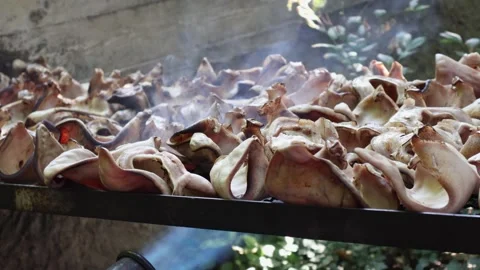 Close-up video of pork ears roasting over an open fire with visible smoke d.. Stock Footage 338199979