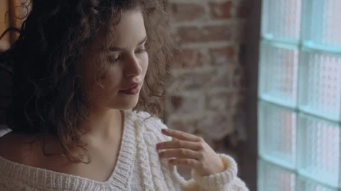 Close up video portrait of young beutiful cute curly girl posing near the window Stock Footage 101511819
