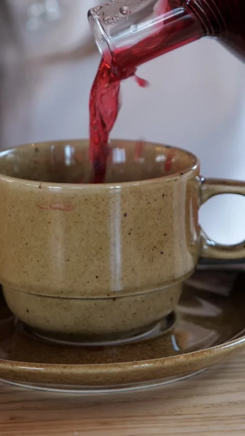 Close up video of pouring a freshly brewed hot red tea from a glass teapot into Stock Footage 345459832