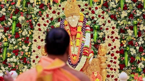 A close-up video of a priest performing puja or aarti to the Sai Baba or Sa.. Video stock 328011475