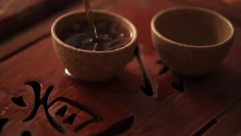 In a close-up video, the process of pouring Chinese Pu-erh tea into two small Stock Footage 249261263