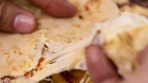 Close-up video of pupusas being cut open by hand, revealing strands of deli.. 動画素材 277789508