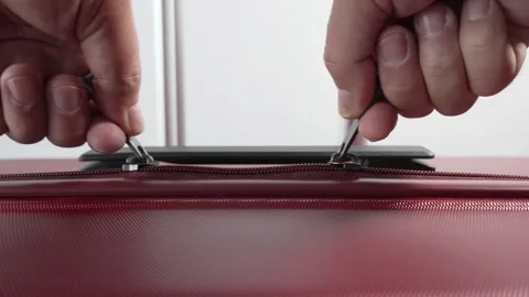 A close-up video shows hands pulling two zippers on a red suitcase. Stock Footage 317083732