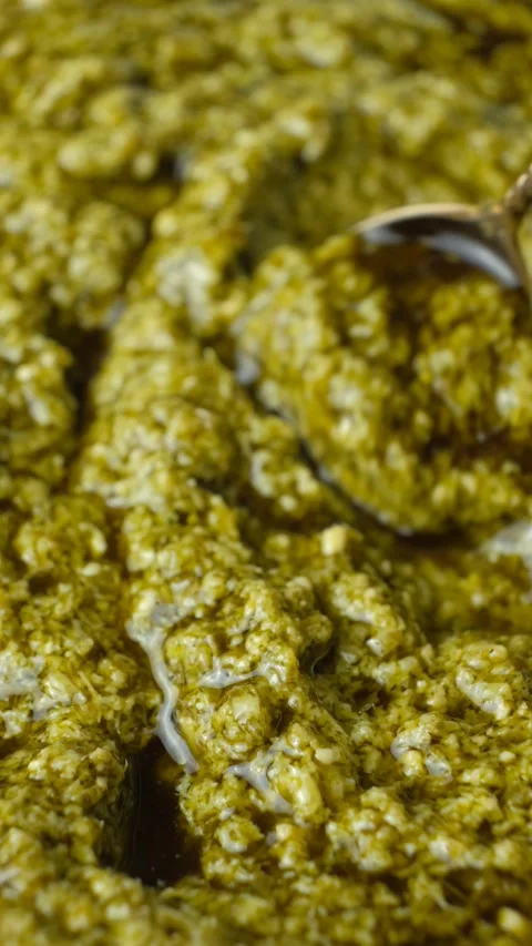 Close-up video of a spoon demonstrating the texture of green basil pesto Stock Footage 340549868