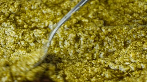 Close-up video of a spoon demonstrating the texture of green basil pesto Stock Footage 344797280