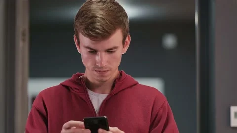 Close up video of a student boy in red hoodie looking for in his mobile phone Stock Footage 159790167