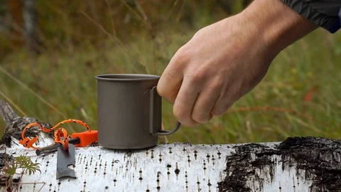 Close-up video of a tourist making tea. Titanium cup on a fallen tree. Stock Footage 117804459
