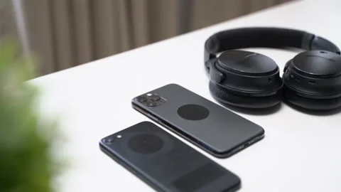 Close up video of two dark smartphone and headphones on a white table Video stock 163862247